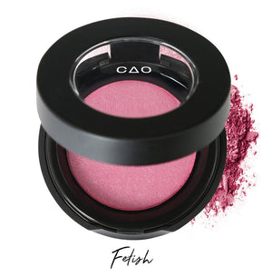 Semi- open eyeshadow compact with bubblegum pink eyeshadow in shade "fetish" compressed powder and on white background with loose eyeshadow powder on white..
