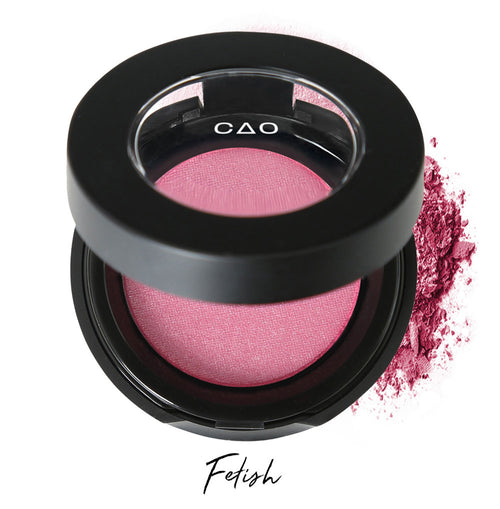 Semi- open eyeshadow compact with bubblegum pink eyeshadow in shade "fetish" compressed powder and on white background with loose eyeshadow powder on white..