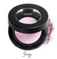 Semi- open eyeshadow compact with lilac colored eyeshadow in shade "sassy" compressed powder and on white background with loose eyeshadow powder on white..