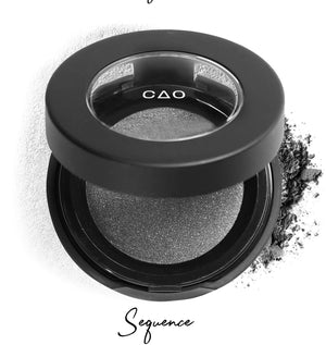 Semi- open eyeshadow compact with silver eyeshadow in shade "sequence" compressed powder and on white background with loose eyeshadow powder on white.