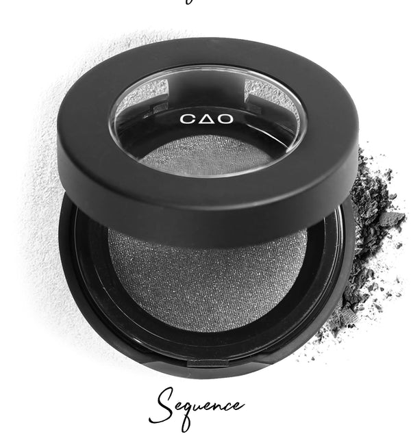 Semi- open eyeshadow compact with silver eyeshadow in shade "sequence" compressed powder and on white background with loose eyeshadow powder on white.